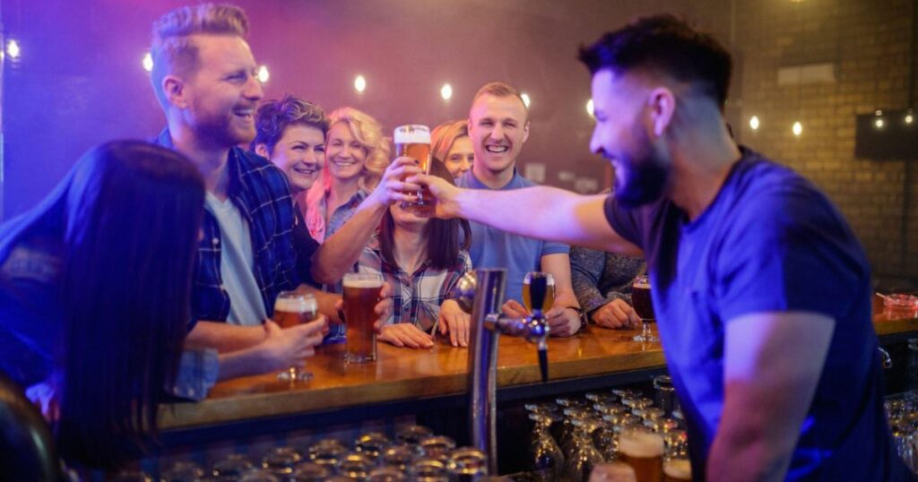 Bartender passing a glass of beer to cheerful woman