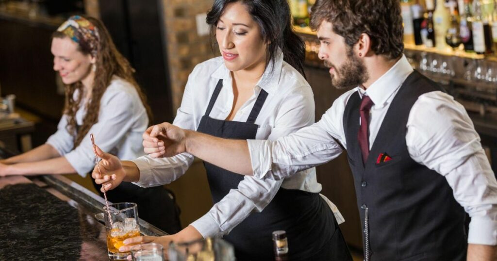 Manager in bar training new bartender to make mixed drinks