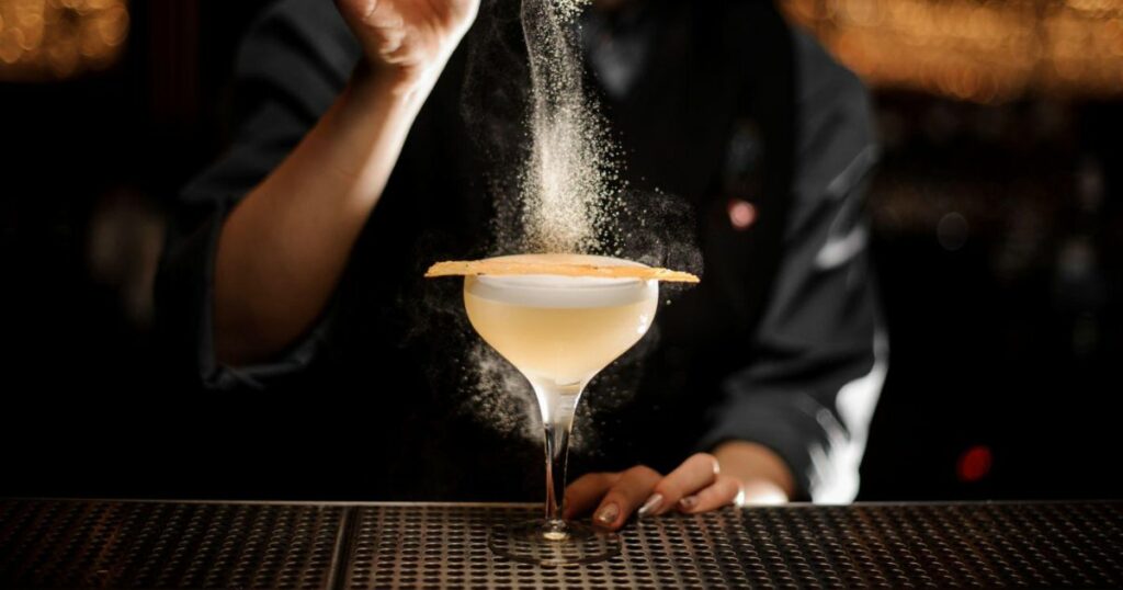 Bartender pours an alcohol cocktail in glass